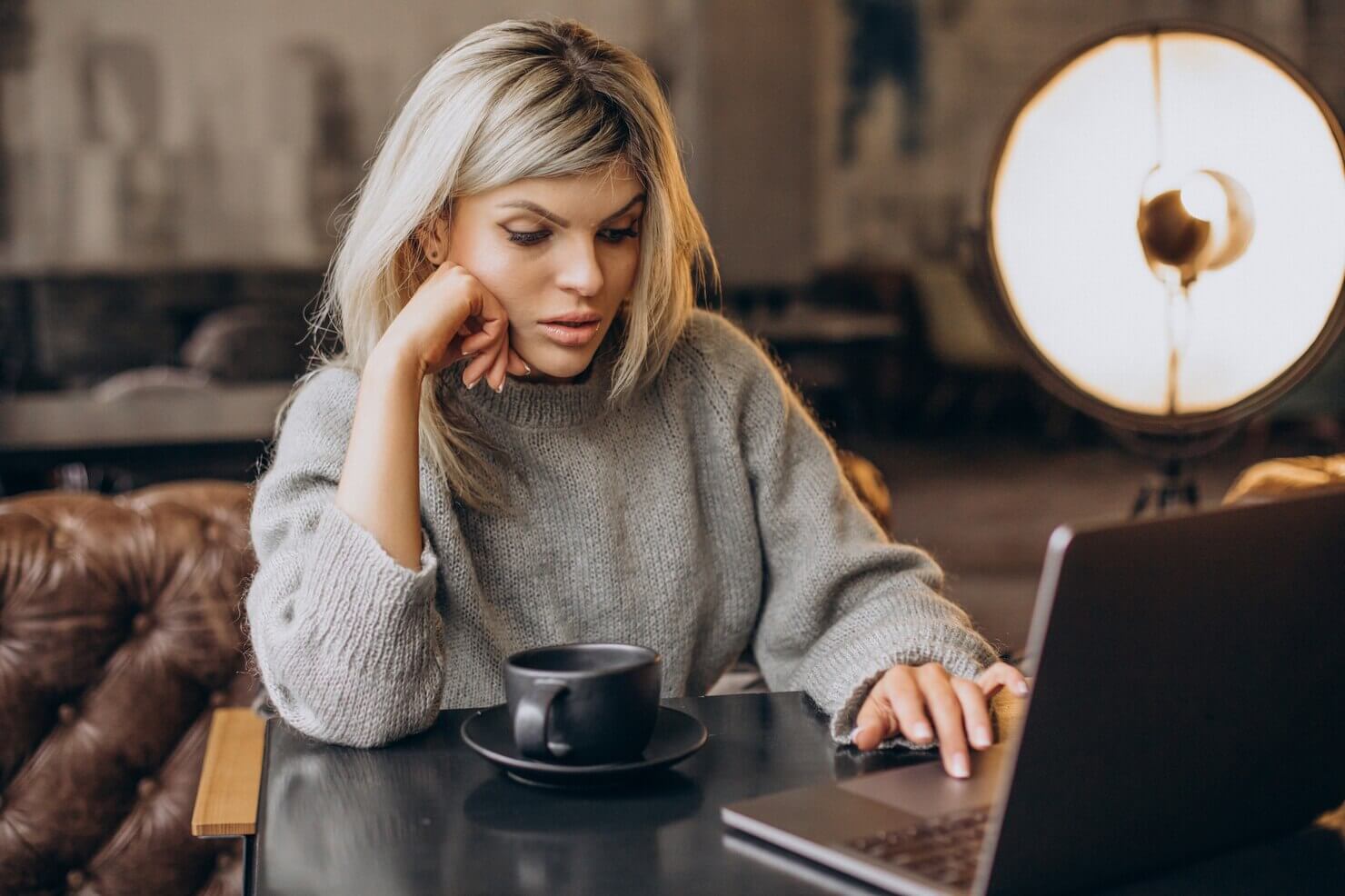Business woman working on computer in a cafe. She is looking to audit your e Commerce product pages