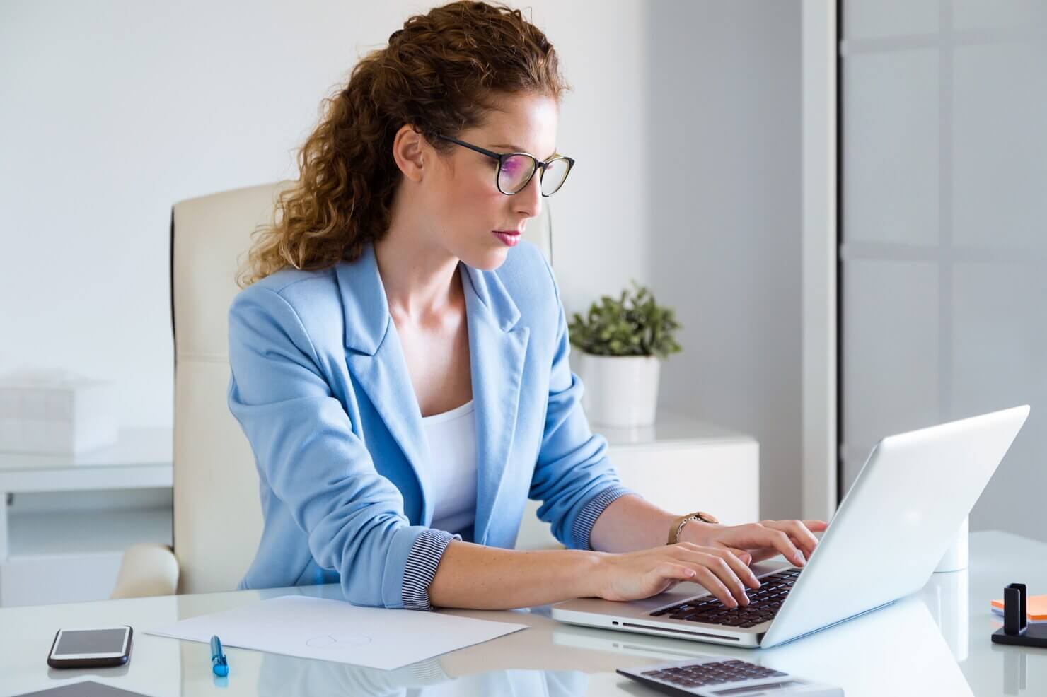 Businesswoman working with her laptop in the office. She is creating a report about hidden costs of poor WordPress development