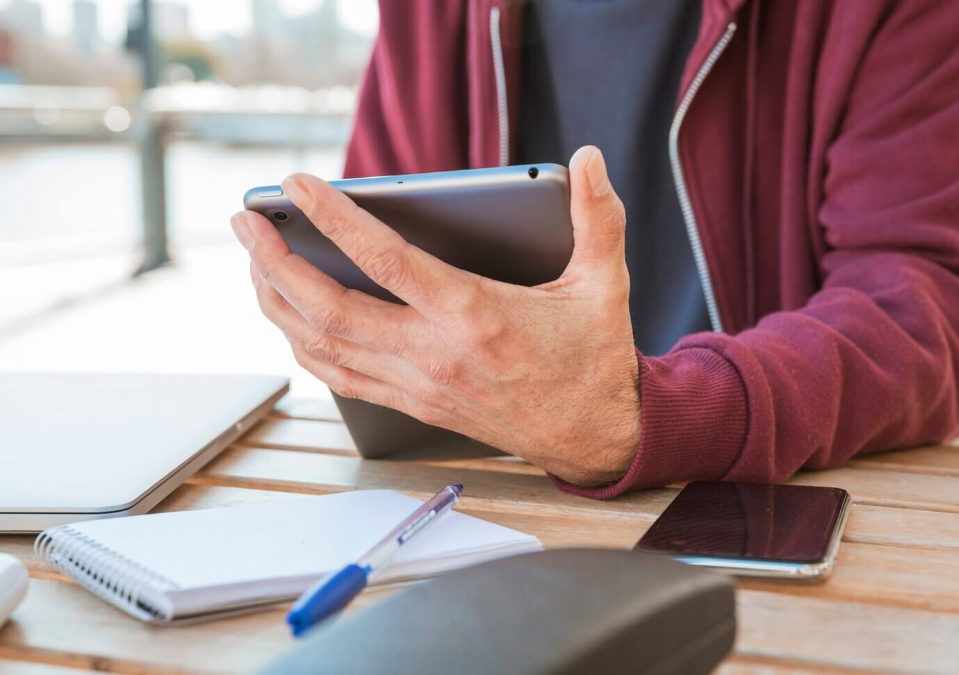 Close-up of man's hand holding digital tablet in hand at outdoors cafe. Mobile usability is key for your website