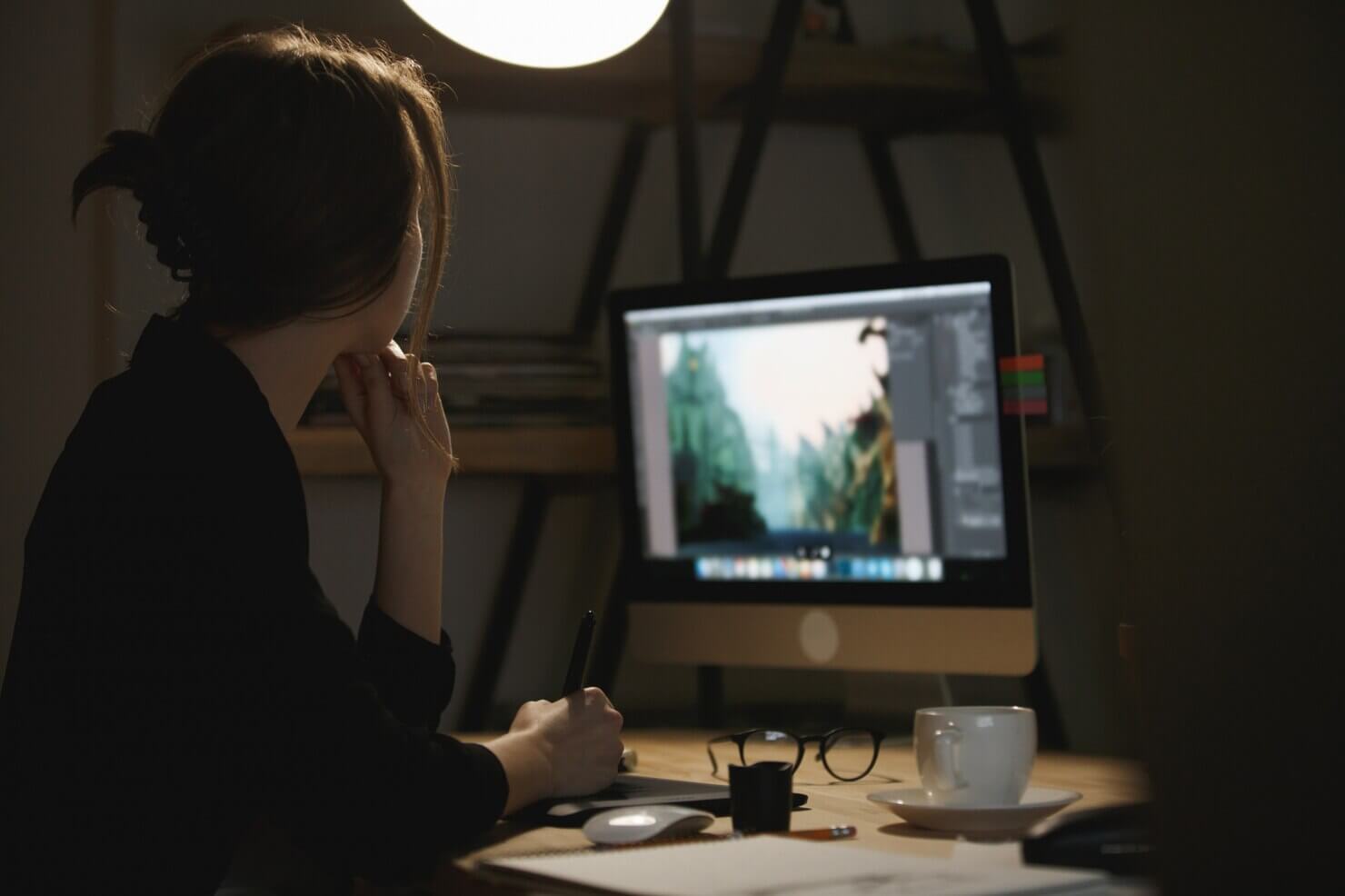 Concentrated young lady designer at night using computer. Preparing files for developers and wordpress installation