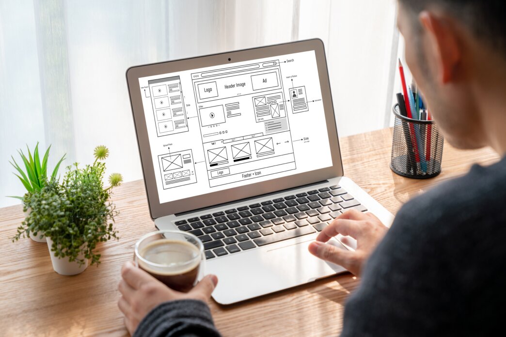 Graphic designer balancing aesthetics and usability in web design process on laptop