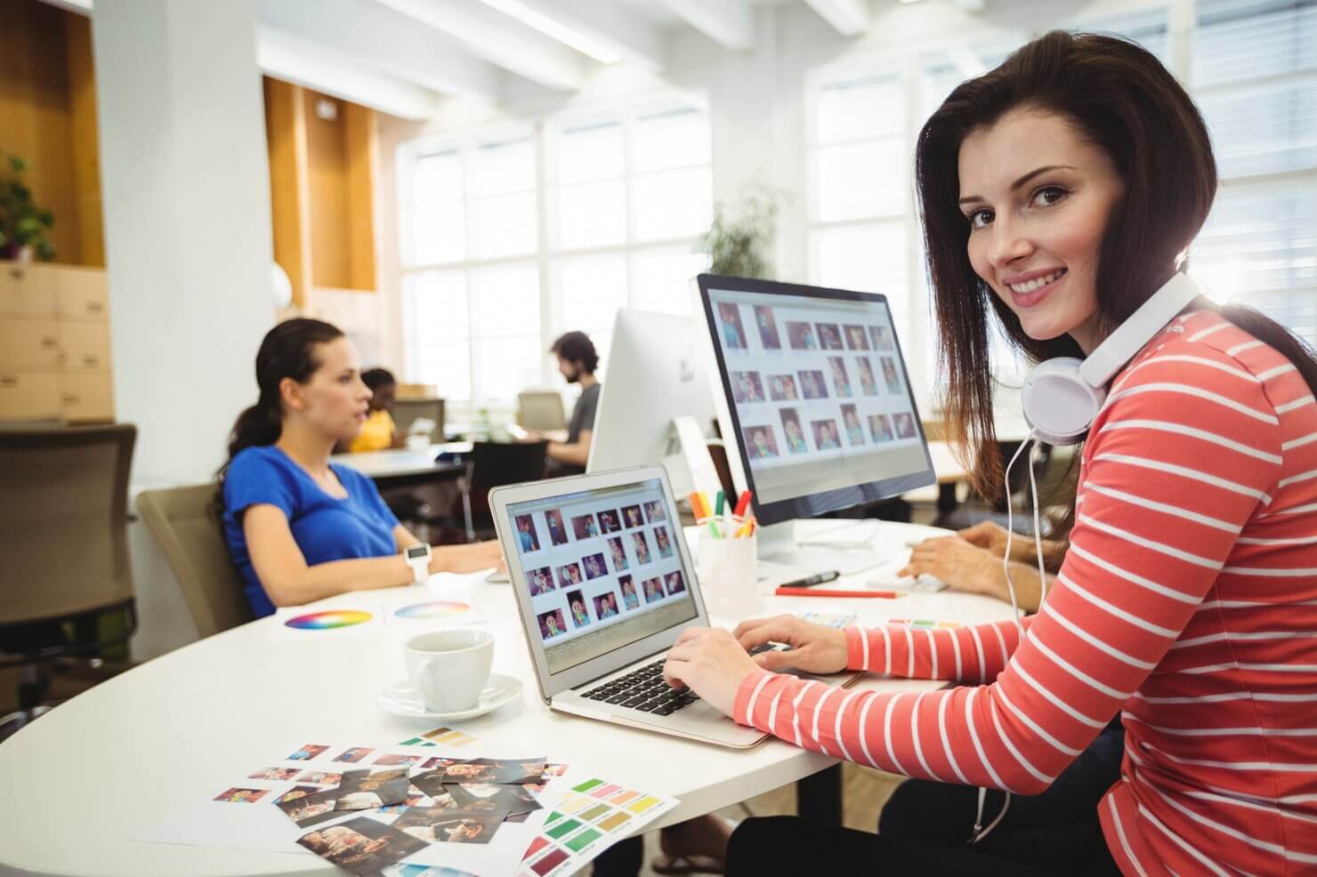 Graphic designer looking at camera while colleague working on functional design