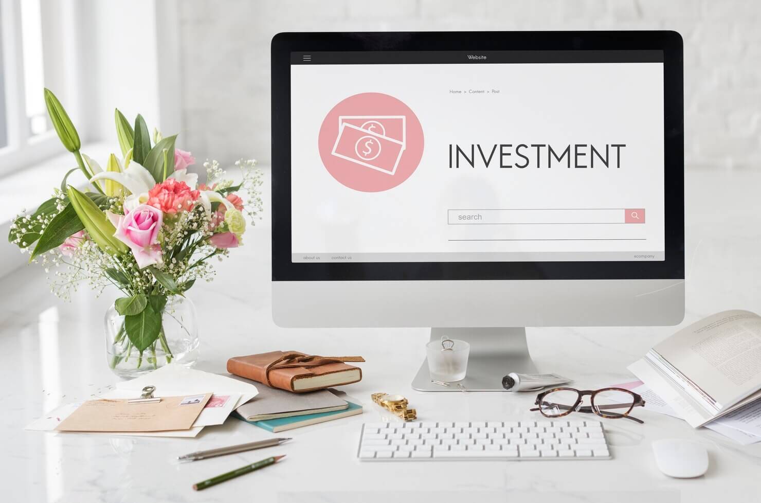 Investment banking webiste on computer screen in a minimal office space with flowers