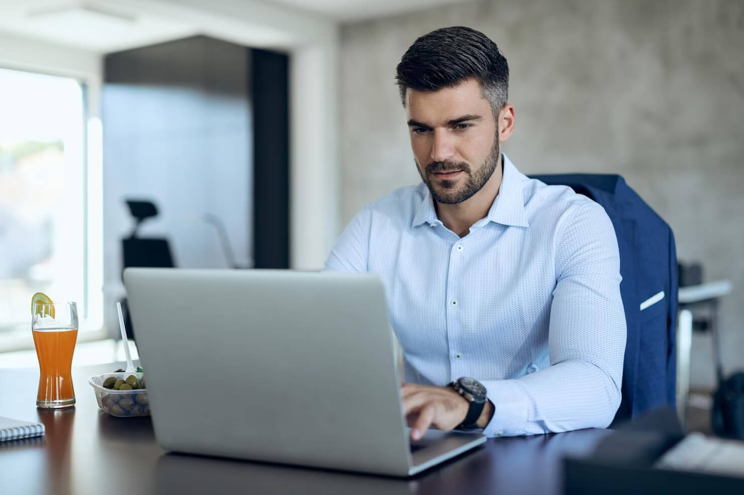 Male entrepreneur using computer while working in the office. He is visiting a a website when pages load faster. Site speed is important to him