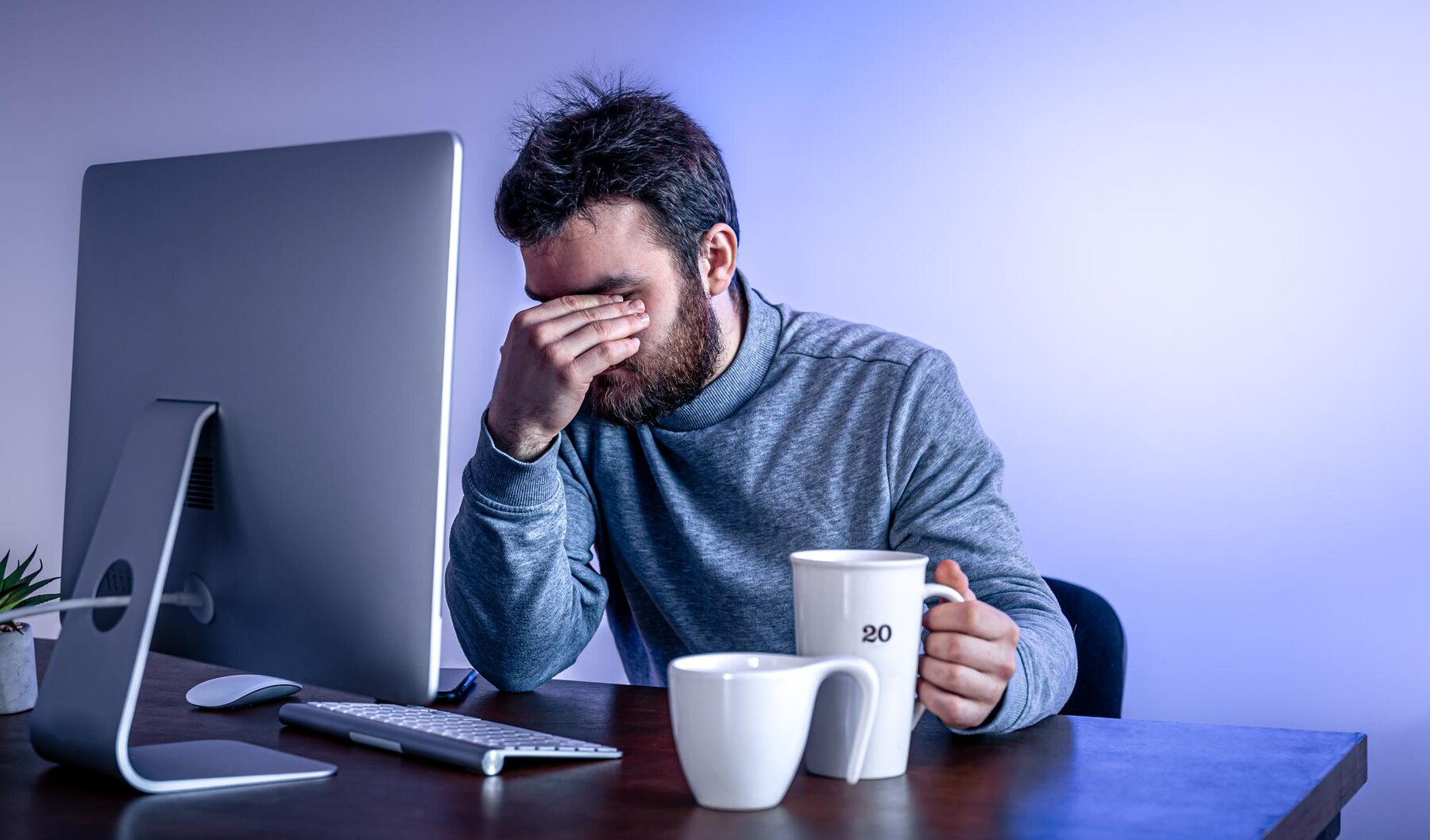 Man sits in front of a computer with a cup of coffee colored lighting. He doesn't have the expertise to carry out a project