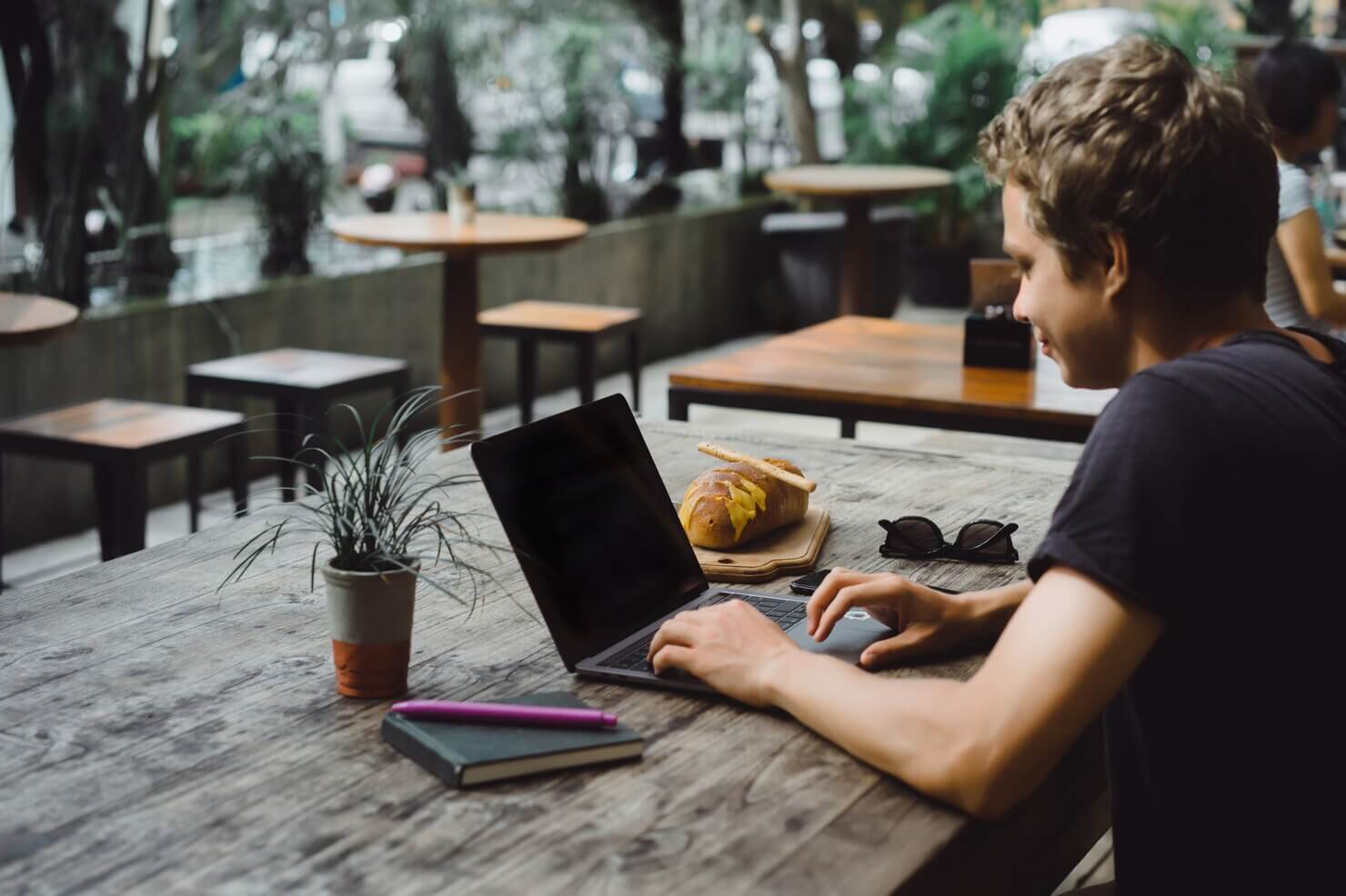 man working with a laptop in a cafe on a wooden table. He is navigating WordPress website