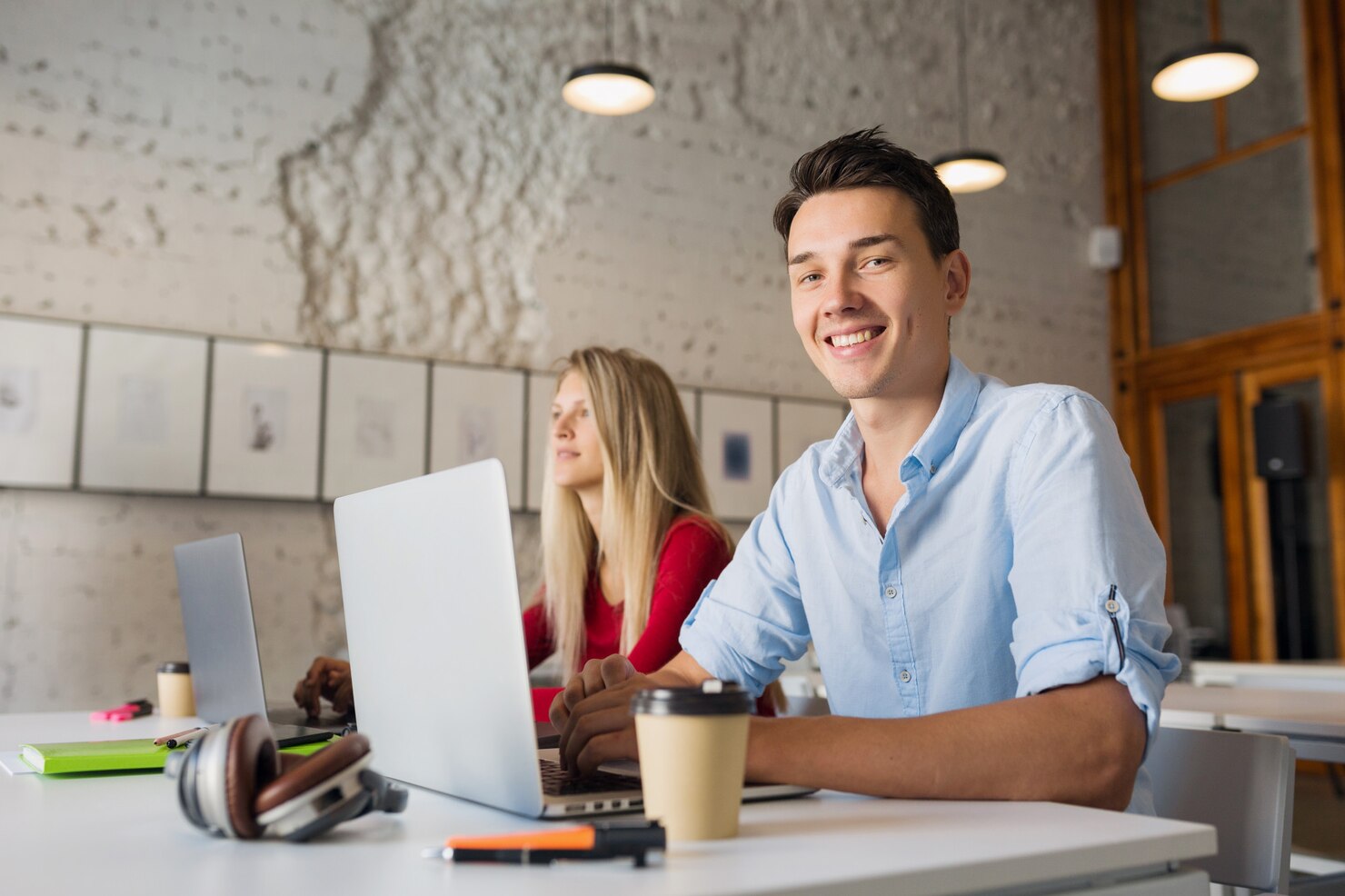 Modern young man and woman working on laptops to create a one page WordPress site using a theme builder on a web hosting service