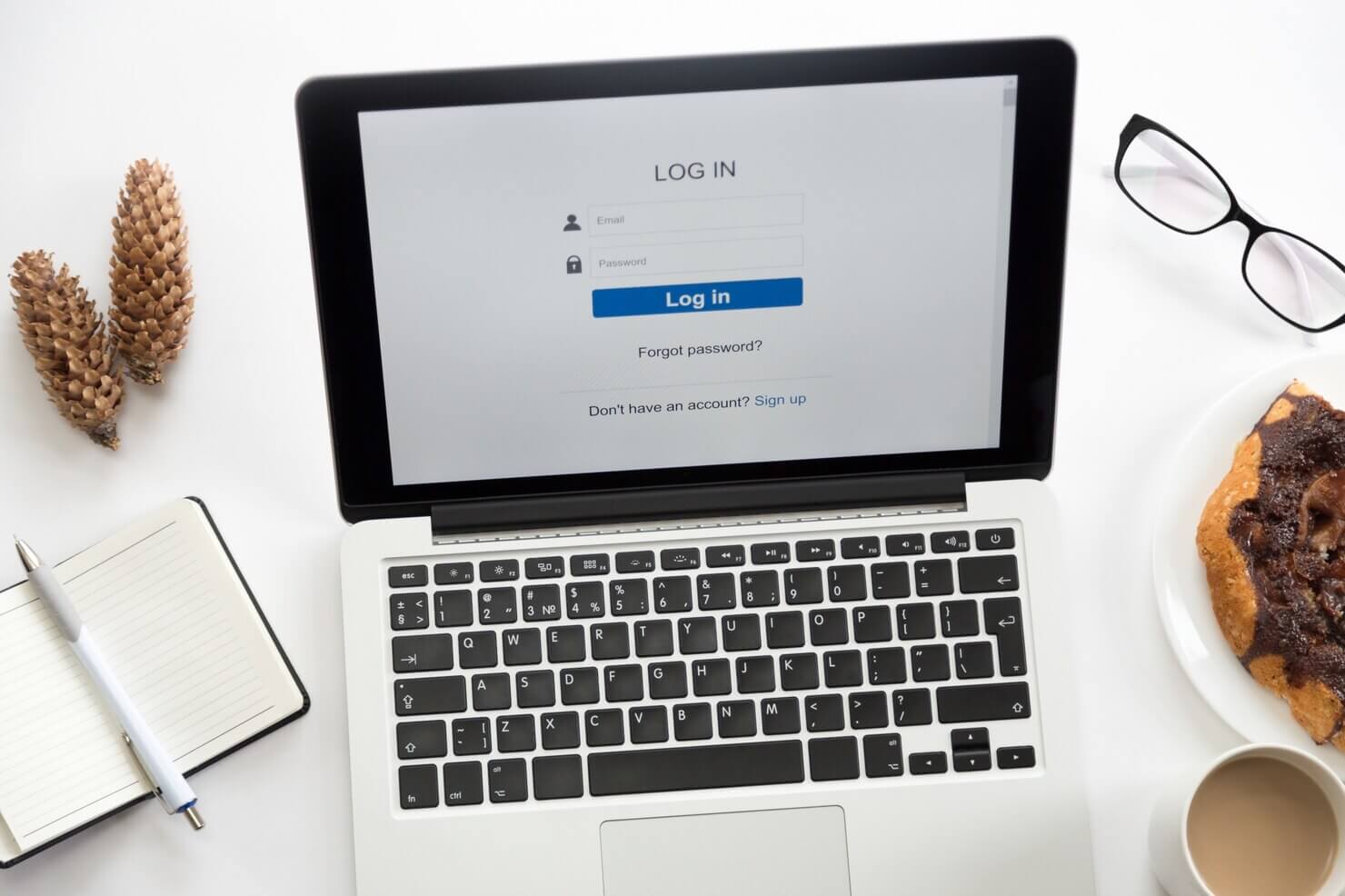 Open laptop with a log in on it, glasses, office supplies. Insecure log in pages is one of the worst WordPress security mistakes