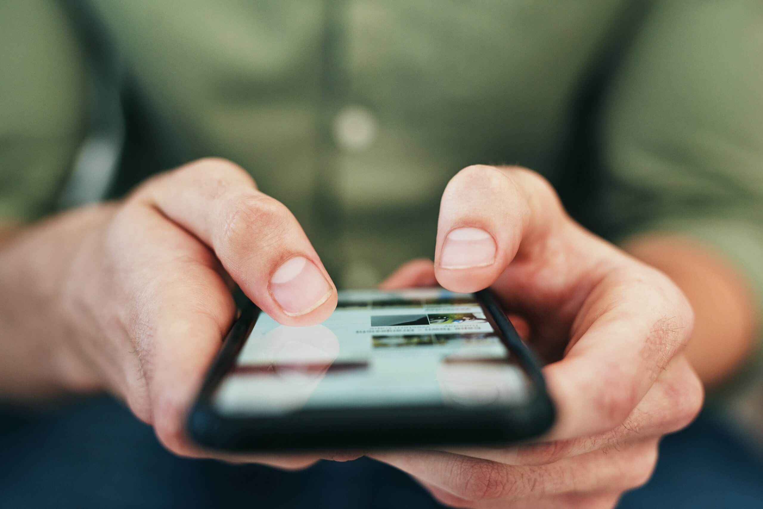 Person scrolling through the internet on a mobile phone. Crafting long form content in WordPress for mobile devices