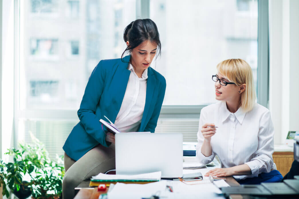 Two female co-workers discussing website audit trends