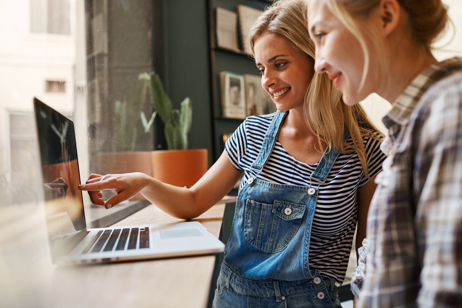 Two female friends sitting inside cafe working on a one-page WordPress site