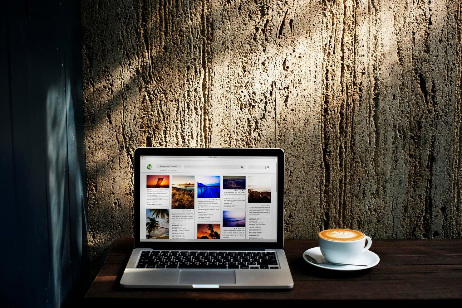 Website content ogranized on a laptop screen with a cappucino beside it on a wooden background