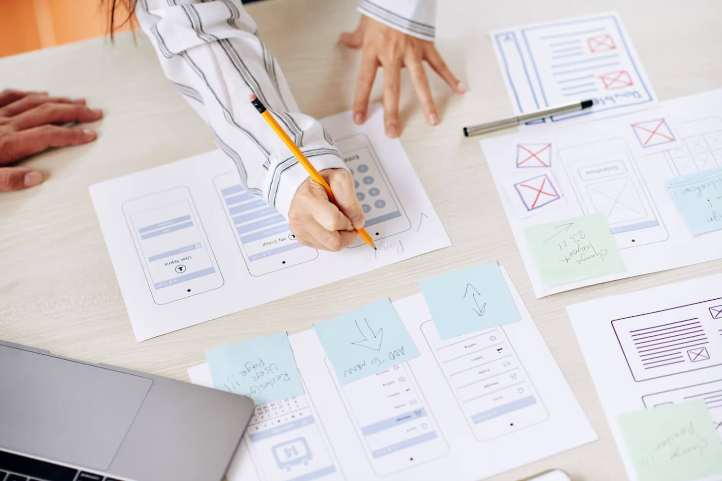 Woman making website interface designs on paper for mobile devices