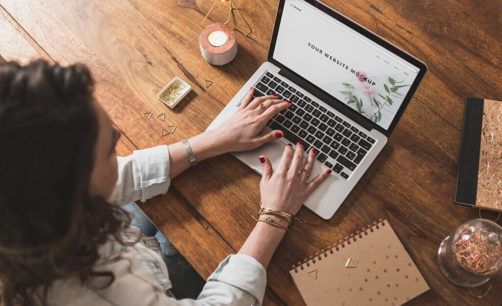 Woman working with laptop on wooden table. She made a choice between WordPress vs Wix for her startup company