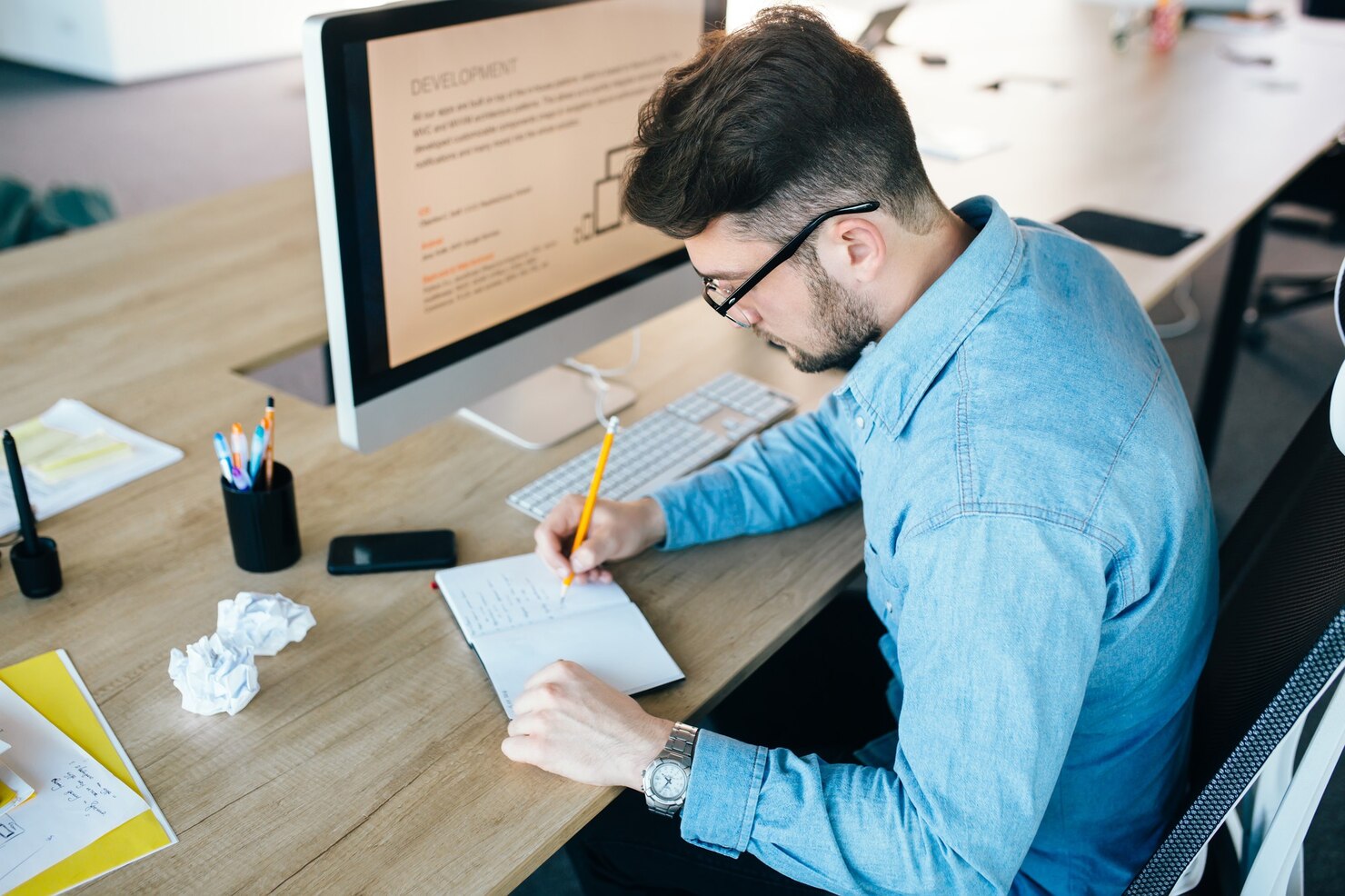 Young man taking notes to compare the results of an A:B test. He start usability testing to gain more users