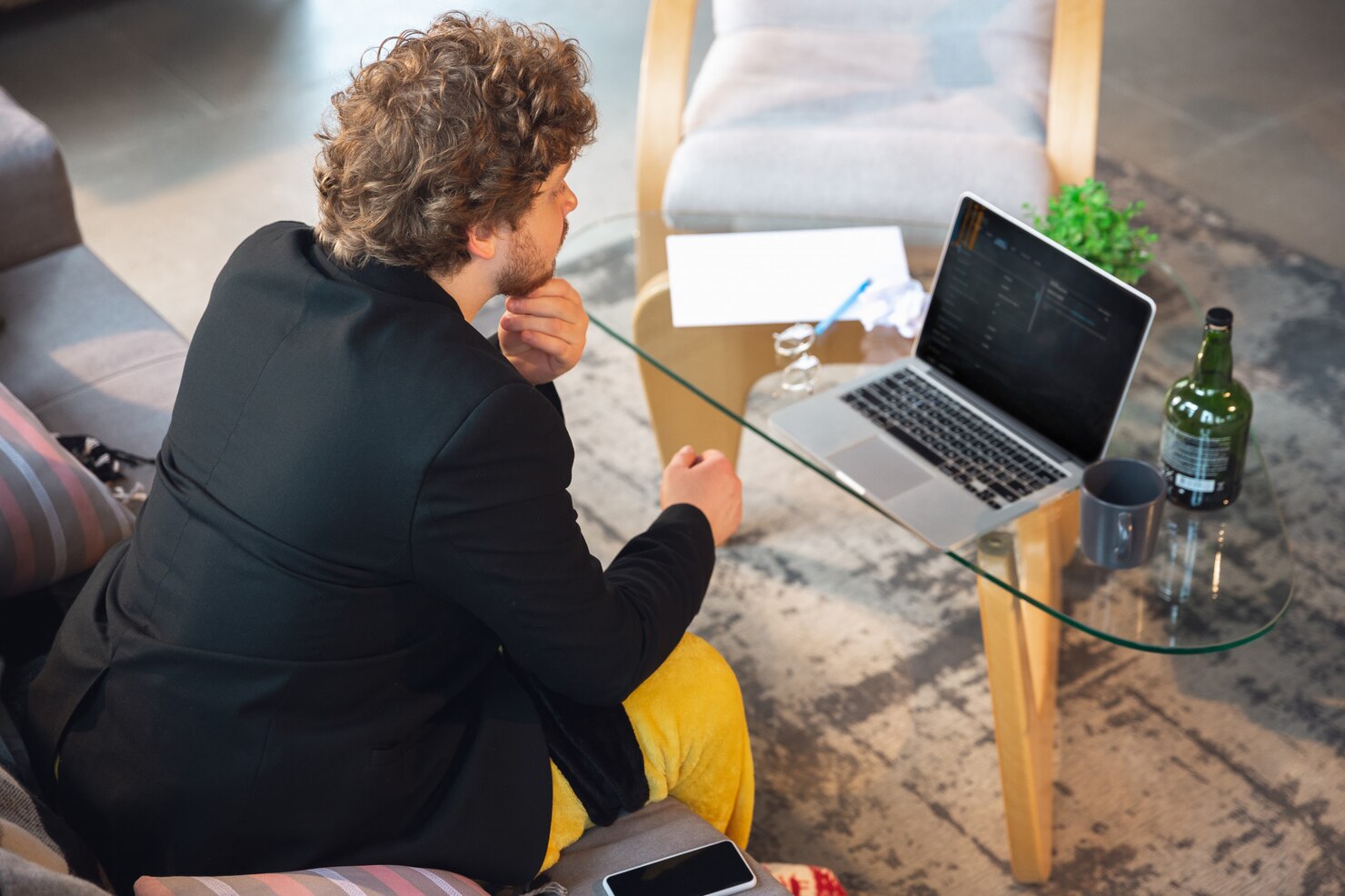 Young man without pants but in jacket working on a computer. Doing reserach between WordPress vs Squarespace
