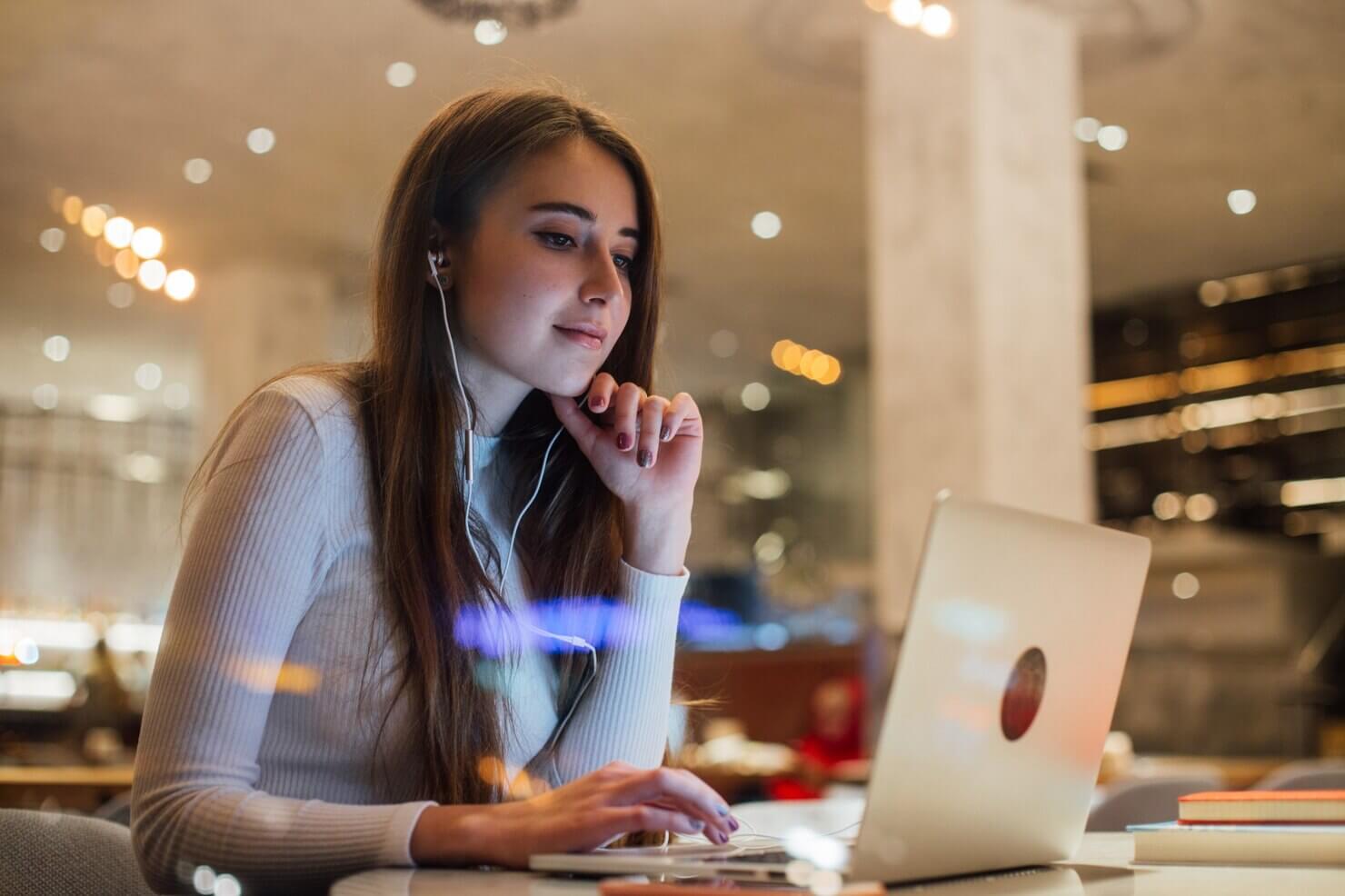 Young woman works on laptop in earphones in office. She working on her blog on WordPress unlike Wix it's the better option